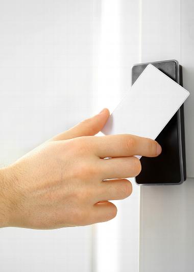 Close up of hand with fob card tapping it on access control box