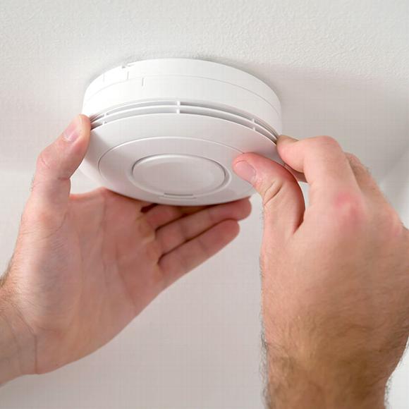 Close up of man installing fire alarm to ceiling