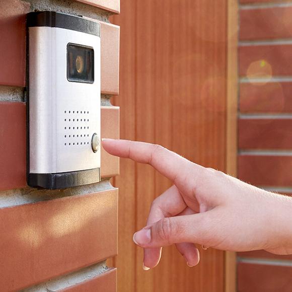 Person pressing button on outdoor intercom system