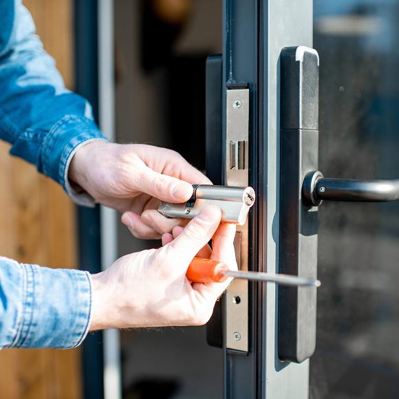 Man replacing lock in glass door